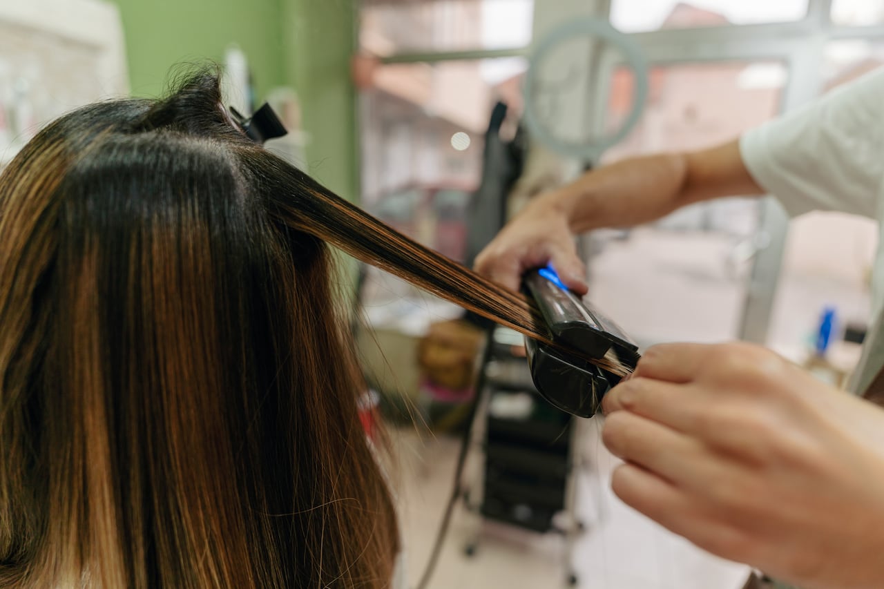 Photo of a hairstylist straightening his customer's hair.