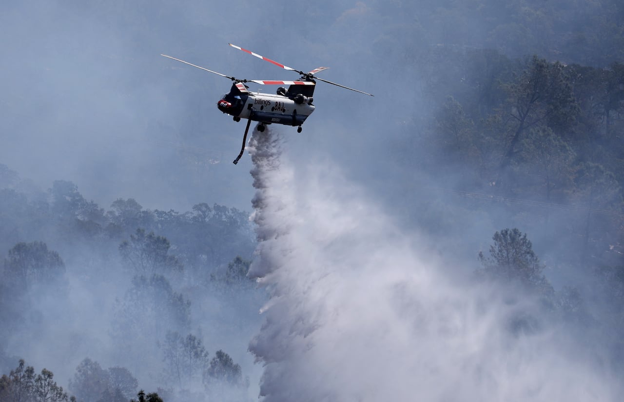 Un helicóptero de extinción de incendios arroja agua sobre el incendio Thompson el 3 de julio de 2024 en Oroville, California.