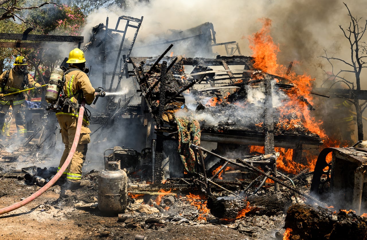 Los bomberos derriban un incendio estructural que se encendió a partir de un generador en llamas y se extendió brevemente a un pequeño incendio en una casa durante el incendio Thompson en Oroville, California, el 3 de julio de 2024.