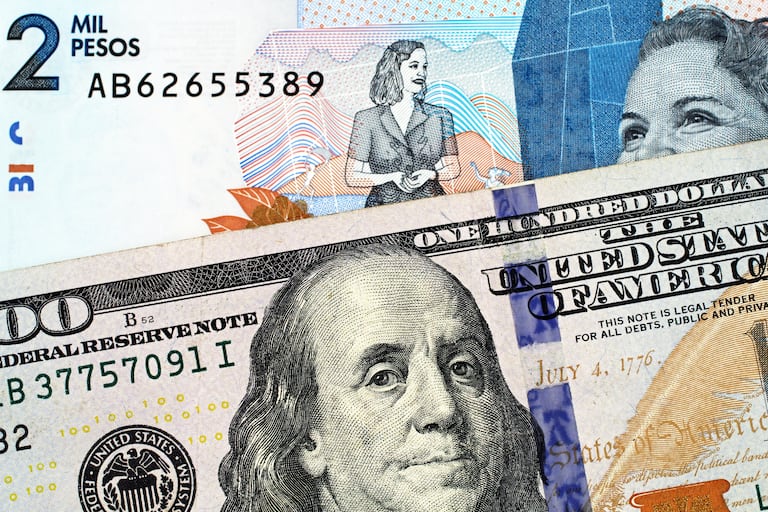 A macro image of a blue, two thousand Colombian peso bank note with a blue, crisp American one hundred dollar bill close up