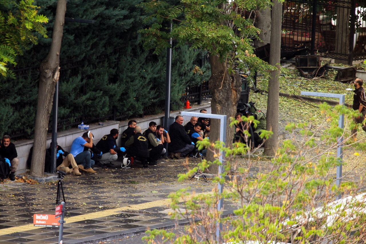 Agentes de policía turcos se cubren mientras expertos en desactivación de bombas trabajan en un área después de una explosión en Ankara, el domingo 1 de octubre de 2023.