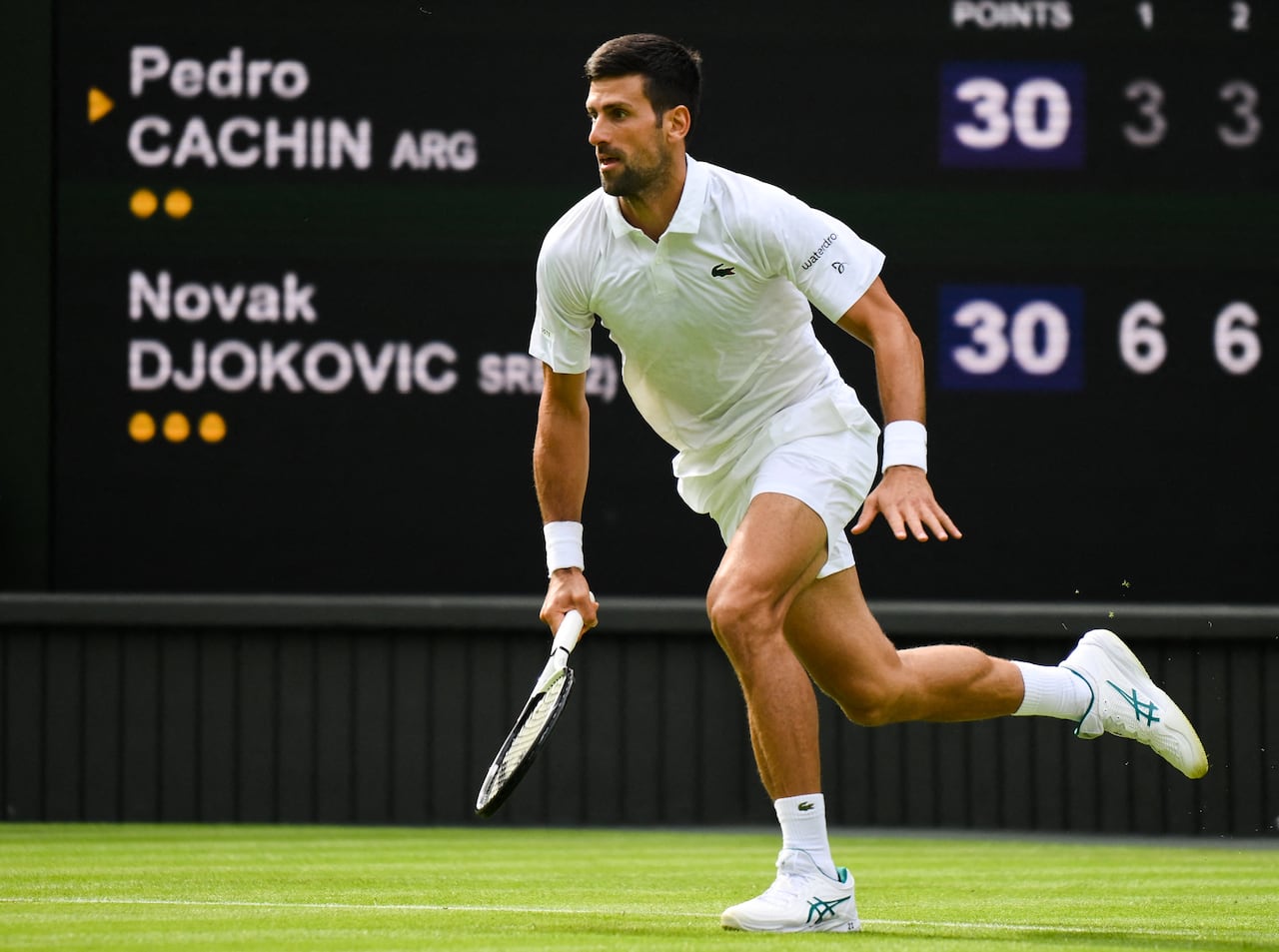 El tenista serbio Novak Djokovic corre por la bola durante un juego ante el argentino Pedro Cachin durante su partido de Wimbledon 2023.