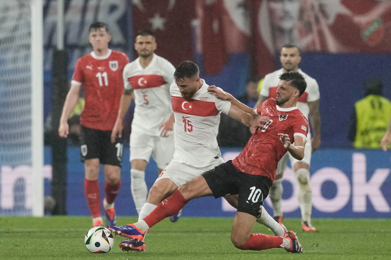 El austriaco Florian Grillitsch, derecha, y el turco Salih Ozcan luchan por el balón durante un partido de octavos de final del torneo de fútbol Euro 2024 en Leipzig, Alemania, el martes 2 de julio de 2024. (Foto AP/Thanassis Stavrakis)