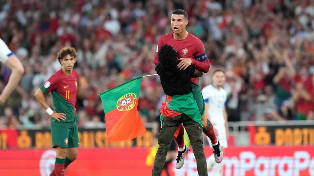 Un invasor de campo atrapa a Cristiano Ronaldo de Portugal durante el partido clasificatorio del grupo J para la Eurocopa 2024 entre Portugal y Bosnia y Herzegovina, en el Estadio Luz de Lisboa, Portugal, el sábado 17 de junio de 2023. (Foto AP/Armando Franca)