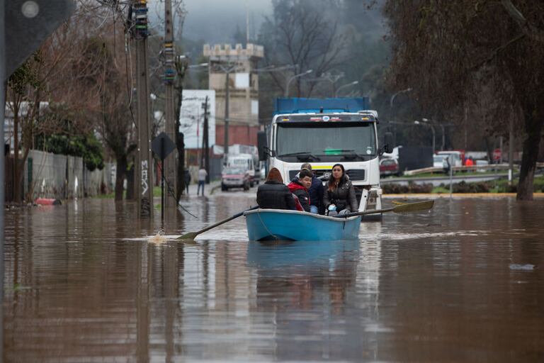 TALCA, CHILE - AUGUST 22: People pass the flooded street with a boat in Talca, Chile on August 22, 2023. Rivers overflowed, and roads damaged, while thousands of Chileans remain isolated or homeless due to torrential rains that have been recorded since last Saturday in the center and south of the country. The National Disaster Prevention and Response Service reported that, in addition to the two deceased, 30,000 people were isolated and 33,895 people were evacuated. (Photo by Lucas Aguayo Araos/Anadolu Agency via Getty Images)