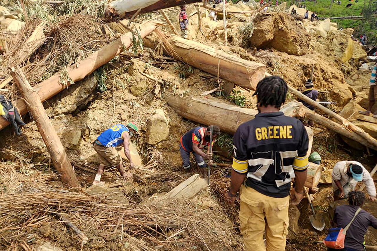 Residentes y equipos de rescate utilizan palas y trozos de madera para encontrar cuerpos bajo el alud.
