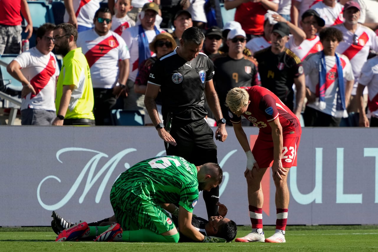 Canada's goalkeeper Maxime Crepeau, his teammate Liam Millar, right, and referee  Mario Escobar, of Guatemala, tend to assistant referee Humberto Panjoj after he fainted during a Copa America Group A soccer match in Kansas City, Kan., Tuesday, June 25, 2024. (AP Photo/Ed Zurga)