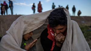 Los migrantes venezolanos Jhak Moremo, de 23 años, y Johana Contreras, de 24, se resguardan del frío mientras se comunican con sus familiares luego de despertarse en el cauce del Río Grande mientras buscaban una entrada a Estados Unidos desde la frontera internacional entre Ciudad Juárez, México y El Paso, Texas, EE.UU., 25 de abril de 2024.