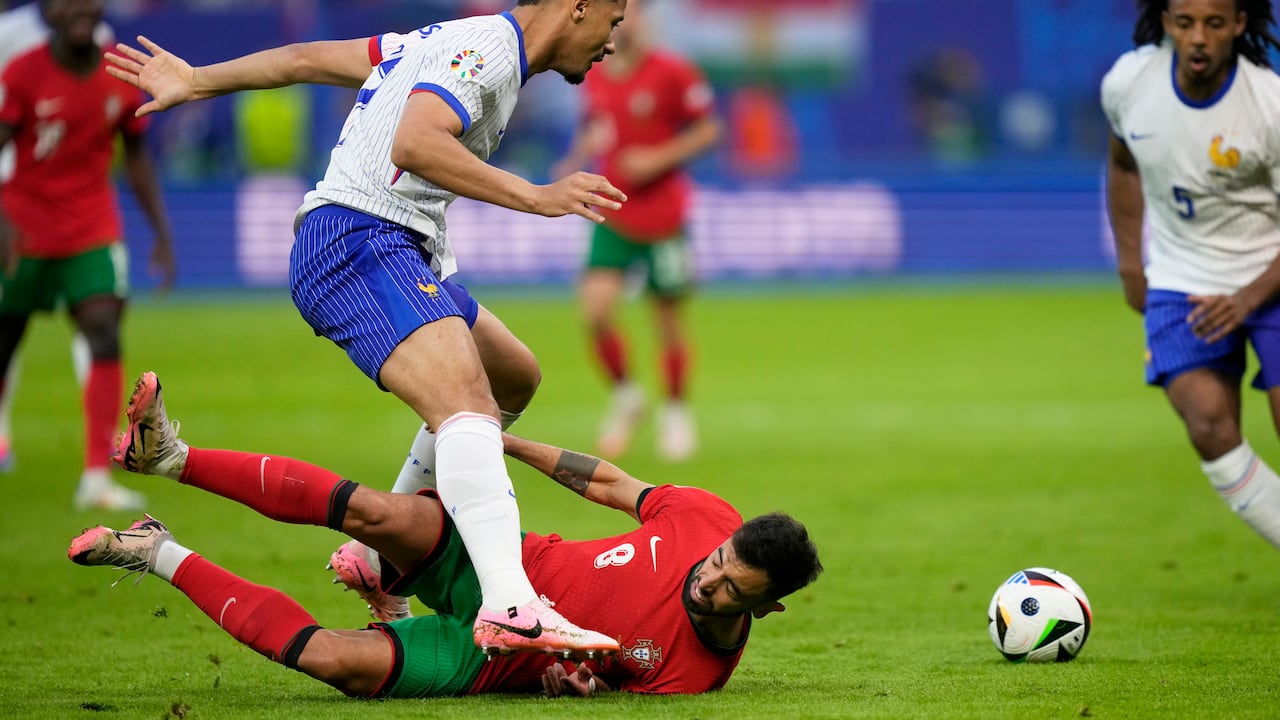 El portugués Bruno Fernandes, en el suelo, intenta enfrentarse a William Saliba de Francia durante un partido de cuartos de final entre Portugal y Francia en el torneo de fútbol Euro 2024 en Hamburgo, Alemania, el viernes 5 de julio de 2024. (Foto AP/Martin Meissner)