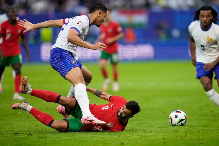 El portugués Bruno Fernandes, en el suelo, intenta enfrentarse a William Saliba de Francia durante un partido de cuartos de final entre Portugal y Francia en el torneo de fútbol Euro 2024 en Hamburgo, Alemania, el viernes 5 de julio de 2024. (Foto AP/Martin Meissner)