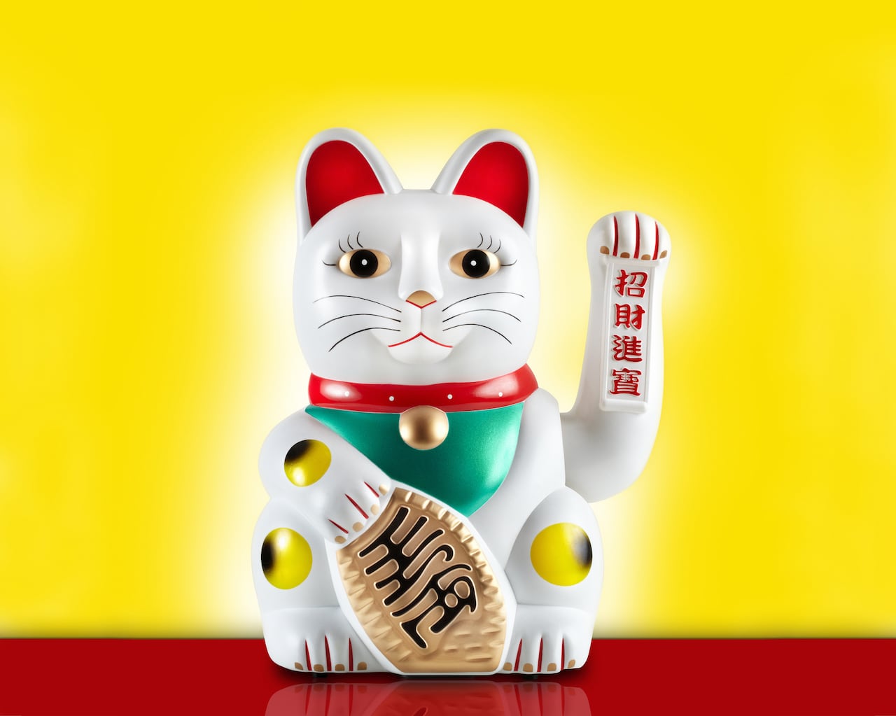 Studio photograph of the statuette known as Lucky Cat or Maneki-neko. This is a Japanese icon that typically represents good luck, and is also known as  Welcoming Cat, Money Cat, or Fortune Cat. The Lucky Cat is often thought to be Chinese since it is often sold through Chinese retailers.