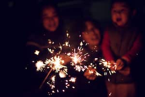 A child is playing sparklers with his family at night