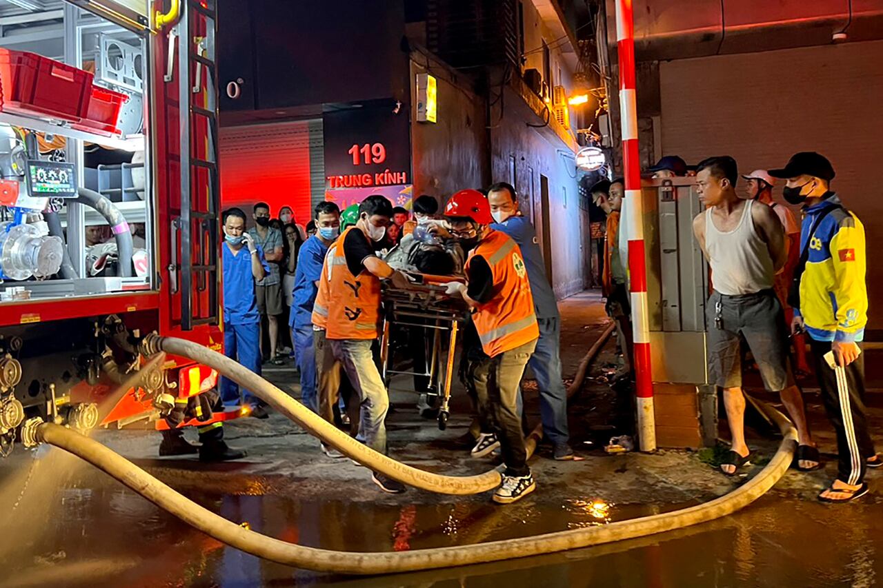 Los trabajadores de bomberos y rescate llevan a una víctima a una ambulancia luego de un gran incendio en un bloque de apartamentos en Hanoi el 24 de mayo de 2024.