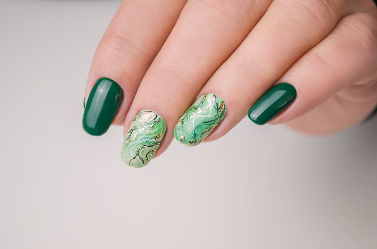 Hands of a young woman. The nails are covered with green gel Polish. Manicure ideas.