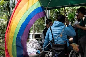 Miembros de la comunidad LGBTI, uno de ellos en silla de ruedas, permanecen encadenados a un banco para protestar por la falta de atención a sus demandas de género frente al edificio de la Defensoría del Pueblo en Caracas el 22 de noviembre de 2022. Un grupo de activistas de la comunidad LGBTI permanece encadenado por segundo día consecutivo, exigiendo al gobierno la aprobación de la identidad de género, el matrimonio igualitario y la despenalización de la homosexualidad.
Yuri CORTEZ / AFP
